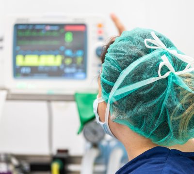 Covid-19 outbreak. Healthcare worker. Nurse working in intensive care unit. Mechanical ventilation system in the background .
