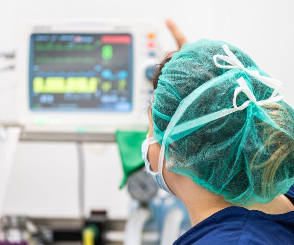 Covid-19 outbreak. Healthcare worker. Nurse working in intensive care unit. Mechanical ventilation system in the background .